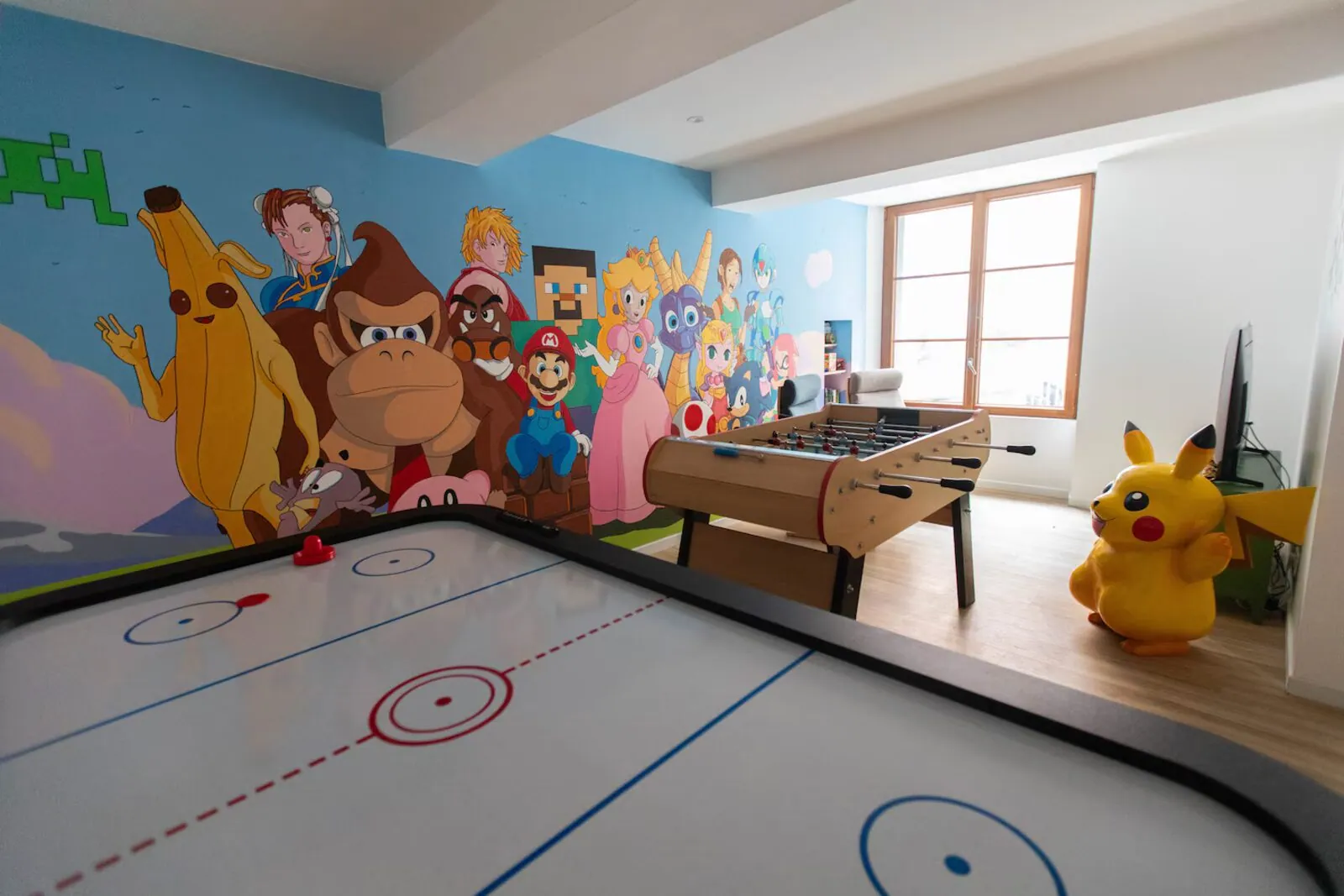 Salle Chill & Play : air hockey, baby-foot et fresque personnages – maison gaming groupes